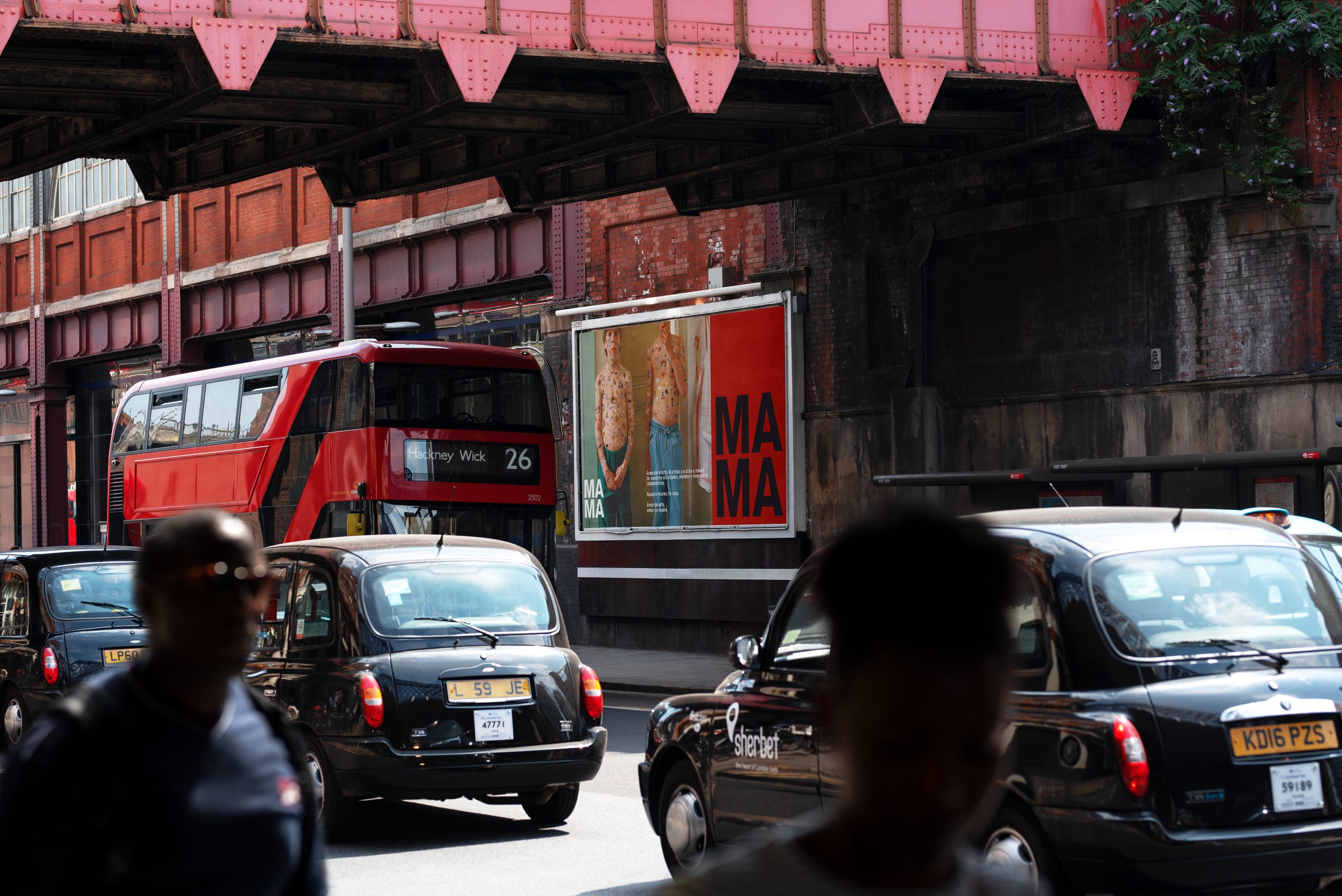 MAMA poster campaign on a London street, with a red bus and black cabs